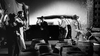 In a black-and-white scene from The Rise and Fall of Legs Diamond (1960) DVD, men in suits and hats break open barrels, splashing liquid, as others raise their hands. A vintage car and wooden crates are seen in the background.