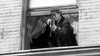 A man in a suit and hat aims a rifle out of a curtained window in this striking black-and-white scene from The Rise and Fall of Legs Diamond (1960) DVD.