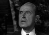 A man in a suit and tie stares wide-eyed in shock in this black-and-white image from the Nightmare Alley (1947) DVD, evoking film noir vibes with its blurred, dark background and faint outlines of trees or stairs.