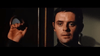 A man with short dark hair and a serious look grips a circular door handle in dim light, evoking scenes from the "When Eight Bells Toll (1971)" DVD.