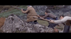 Three men crouch and move up a rocky hillside, rifles in hand and dressed for the outdoors, focused as they advance through rugged terrain—just like a scene from "When Eight Bells Toll (1971)" on DVD.
