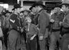 A group of men in old Western attire stand around a young boy in a dusty town as two men, one in military uniform, confront each other—a scene evocative of the Civil War drama in Virginia City (1940) DVD.