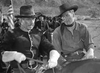 Two men in cowboy hats ride horses, with an American flag behind them—a scene reminiscent of classic Western nostalgia like in Virginia City (1940) DVD starring Errol Flynn.