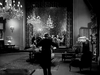 A person in formal attire stands in an elegant, dimly lit room, evoking the timeless allure of The Glass Key DVD (1942), a vintage black-and-white film from Hollywood’s golden era.