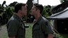 Two men in military uniforms argue intensely face to face at an outdoor camp with tents and greenery—a gripping scene from the Rain (2006) DVD, a classic war drama.