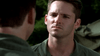 A serious man in a green military uniform faces another person with their back to the camera, against a blurred backdrop of greenery and a vehicle, capturing the tense atmosphere of the Rain (2006) DVD war drama.