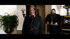 Two men in vintage suits stand indoors; the front man sports gray hair and a red cravat, while a bearded man behind wears dark clothing. Plants and a piano decorate the scene—ideal for fans of rare DVDs like The Ridiculous 6 (2015) DVD.