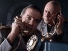 Two men in military uniforms share a rotary phone—one speaks as the other listens, both serious. The dim lighting and tense mood evoke the suspenseful World War II historical drama, Countdown to War (1989) DVD.