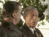 Two older men, one in a dark suit and striped tie, the other in uniform, converse before a leafy backdrop—capturing the tense atmosphere of a World War II drama like Countdown to War (1989) DVD.