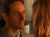 A man in a light suit smiles gently at a blonde woman turned away, bathed in warm, intimate lighting that echoes the suspenseful tone of the "Obsessed (2002) DVD.