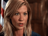 A woman with long blonde hair and blue eyes speaks intensely, unraveling a true-crime drama. An American flag is partially visible behind her, evoking scenes from the "Obsessed (2002) DVD.