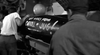 Two people stand by a large bomb with "Best wishes from Cracill & Jug!" in a black and white WWII submarine scene—a perfect pick for classic film fans. Featured in Hellcats of the Navy (1957) DVD, the setting suggests a military or industrial backdrop.