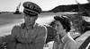 A man in a naval officer’s uniform stands beside a woman with short hair outdoors, evoking a classic WWII submarine drama, as seen in the black and white scene from Hellcats of the Navy (1957) DVD.