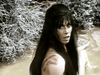 A startled woman with long dark hair and scratches on her shoulder stands in muddy water, echoing a scene from 1970s frontier films. Sparse, pale vegetation appears in the background—just like in Gone with the West (1975) DVD.