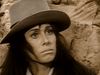 A person with long dark hair and a wide-brimmed hat stands before rocky terrain, mirroring the mysterious frontier mood found in Gone with the West (1975) DVD.
