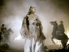 A woman in a flowing dress and shawl stands amid cowboys on horseback and swirling dust—dramatic lighting captures the fierce, misty atmosphere of frontier revenge in Gone with the West (1975) on DVD.