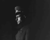 A man in uniform stands in profile, partially lit against a dark background, capturing the wartime drama and suspense of Guerrilla Girl (1953) on DVD.