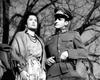 A woman in a patterned skirt and shawl stands by a man in uniform with a peaked cap, bare tree branches behind them—an evocative black-and-white scene from the classic wartime drama "Guerrilla Girl (1953)" DVD.