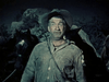 A rugged man in a wide-brimmed hat and worn jacket stands outdoors at night with horses and rocky terrain, capturing the spirit of rare western films like "Kentucky Rifle (1955)"—now available on DVD.
