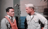 Two men in military uniforms stand on a ship, one with a life vest, the other with a cap, having a serious conversation by the ocean—an intense moment from "Flat Top (1952)" DVD.