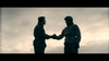 Two people in military uniforms shake hands at dusk under a cloudy sky, capturing the tension and bravery reminiscent of Special Air Service tales, as seen in the film "I Am Soldier (2014)" available on DVD.