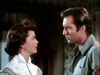 A man and woman gaze intently indoors, evoking the tension of a frontier western showdown. She wears a white blouse; he’s in a grey shirt—capturing the classic cowboy film style in "The Lone Gun (1954)" DVD.