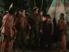 A group of men, some as cowboys and others as Native Americans, stand by a large tipi at night in conversation—evoking a scene from The Cariboo Trail (1950) DVD.