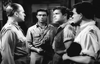 Four men in military uniforms stand together indoors, deep in conversation, evoking the tense atmosphere of classic British war films. This black-and-white image is from "Break to Freedom (1953)" on DVD.