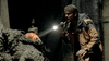A man in an orange and black jacket shines a flashlight onto a glowing orb in the mud, evoking a scene from The Bone Snatcher (2003) DVD—perfect for fans of rare, hard-to-find early 2000s horror movies.