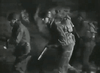 Black and white image of police in riot gear advancing at night, holding batons and shields—evoking scenes from rare classics like Under Fire (1957) DVD.