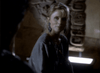 A blonde woman in a gray top and large earrings sits in a dim room with ancient carvings, recalling scenes from "Nick Knight (1989) DVD," a rare 80s TV movie about a vampire detective.