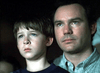 A young boy and an adult man sit close together, both looking ahead with serious expressions, as if they are watching Judgement Day: The Ellie Nesler Story (1999) DVD in a dark, blurred background.