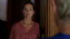 A woman in a pink dress stands in a dimly lit wooden doorway, looking out of frame with a neutral expression—like a scene from the rare "Just What the Doctor Ordered (2021)" DVD.