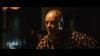 An older man with short hair in a plaid shirt sits indoors in dim lighting, looking serious—resembling a character from "I'll Take Your Dead (2018)" DVD, an unconventional Canadian horror thriller.
