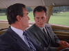 Two men in suits sit across from each other in a car, deep in conversation. Green grass and trees outside the window evoke scenes from the film Promise (1986) DVD.
