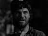 A bearded man in a coonskin cap smiles faintly and gazes sideways outdoors in this black-and-white image from "The Iroquois Trail (1950) DVD," evoking the spirit of frontier adventure and classic cinema.
