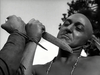 A bald man in a necklace is threatened with a knife in this tense black-and-white scene from The Iroquois Trail (1950) DVD—a must-see for fans of classic frontier adventure movies.