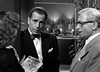 A man in a suit and bow tie stands beside another suited man with glasses, talking to a woman holding Mother Bride magazine in this black-and-white scene from the In A Lonely Place (1950) DVD.