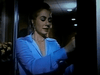 A woman in a light blue outfit stands in a dimly lit room, facing a dark doorway with a concerned expression on her face—an image reminiscent of scenes from rare classic movies like “Winner Take All (1975)” DVD. Ceiling lights and flowers are visible in the background, evoking the dramatic tension characteristic of compulsive gambling drama films.