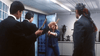 A woman holding a gun confronts three men in suits—two brandishing sticks—inside a brightly lit room with blue windows and office furniture, capturing the electrifying action of Cynthia Rothrock’s classic Hong Kong film, “City Cops (1989) DVD,” a sought-after rarity among collectors of martial arts movies.