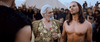 An older man in ornate gold robes adorned with jewels stands beside a shirtless, long-haired man; both are surrounded by soldiers clad in brown and black armor, with a tent set behind them—creating a striking scene reminiscent of a biblical epic such as the “One Night with the King (2006) DVD.”.