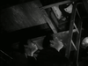 Two men look up from a dimly lit cellar as a uniformed officer peers down at them through an open trapdoor. A ladder connects the figures in the confined, shadowy space—a tense moment evocative of scenes from The Wooden Horse (1950) DVD, a classic British war film and a sought-after title among rare, hard-to-find movies.