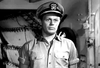 A man in a naval officer’s cap and short-sleeve uniform stands indoors, his serious expression captured in a black-and-white scene from The Frogmen (1951) DVD; this gripping moment captures the tension of WWII underwater demolition thrillers, showcasing the appeal of rare hard to find movies.