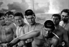 Seven shirtless men wearing dog tags and goggles stand together in water, their tense and serious expressions evoking the high-stakes atmosphere of a WWII underwater demolition thriller. Smoke or mist rises dramatically in the background, heightening the sense of danger. Presented in stunning black and white, The Frogmen (1951) DVD is a rare and hard-to-find classic that captures the intensity of vintage wartime cinema.