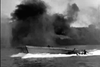 A military boat speeds across the water with heavy black smoke rising in the background, evoking an explosive battle scene reminiscent of a WWII underwater demolition thriller—perfect for fans searching for rare hard-to-find movies and classic films on DVD like The Frogmen (1951) DVD.