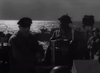 Black and white photo of soldiers aboard a ship at sea, sunlight glinting on the water—a striking image evoking the tense atmosphere of Glory at Sea (1952) DVD, where helmeted men in uniform stand near metal equipment while others linger in the background, reminiscent of classic British naval war dramas frequently featured among classic movies on DVD.