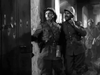 Two soldiers in uniform stand by a bullet-riddled door in a dim hallway, alert and tense—capturing the suspense of WWII espionage as seen in Operation Secret (1952) DVD, a hard-to-find rare movie.