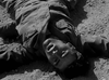 A man in a military uniform lies on his back on rough ground, looking up with his mouth open, appearing distressed or exhausted—capturing the gritty realism featured in the 1958 war film "Hell Squad," now available on DVD.