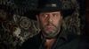 A bearded man in a black hat and shirt looks to the side with a serious expression, standing before a patterned tapestry backdrop—evoking the timeless allure of classic characters from rare western movies like The Savage Guns (1962) DVD, which captures the spirit of the Spaghetti Western era.