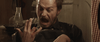 A bearded man stares in shock and horror at his bloody hand, mouth agape, as he sits in a dimly lit room illuminated by an oil lamp—a gripping moment straight from Kill or Be Killed (2015) DVD, evoking the intense, neo-western crime thriller atmosphere that makes this film a rare gem for collectors.